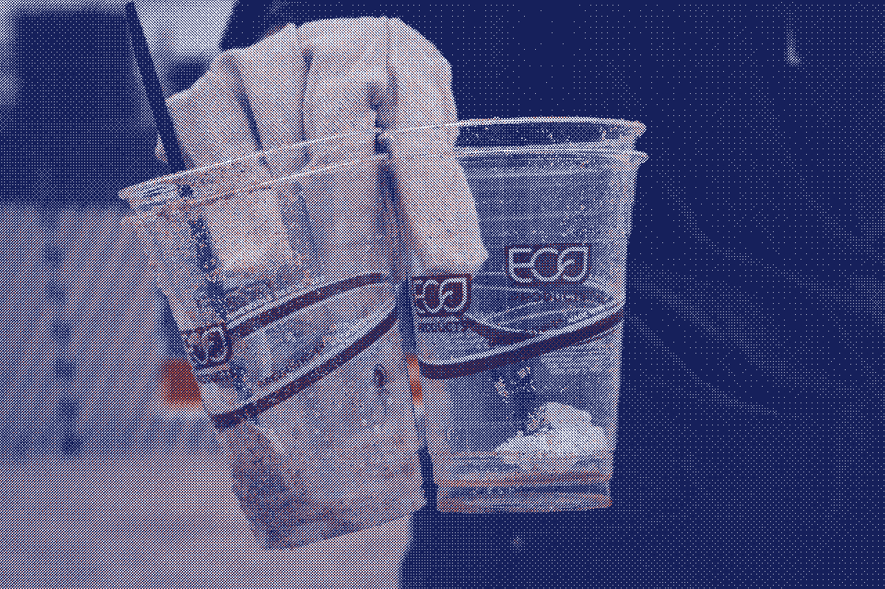 Main gantée tenant des cups en plastique étiquetés 'eco', illustrant le greenwashing dans l’industrie des protections périodiques - Marguerite & Cie