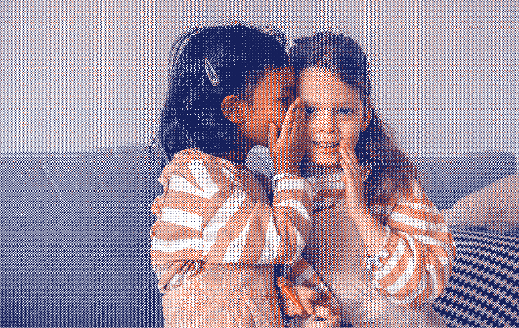 Deux petites filles assises sur un canapé l une chuchote à l autre symbole de sensibilisation aux protections périodiques - Marguerite & Cie